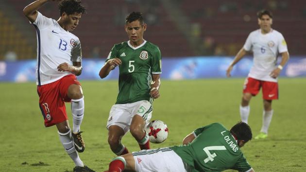 Mexico's Luis Olivas (on the ground) and Raul Sandoval fight for the ball with Chile's Yerco Oyanedel (left) during their FIFA U-17 World Cup Group F football match in Guwahati on Saturday. Get highlights of the Mexico vs Chile match here.(AP)