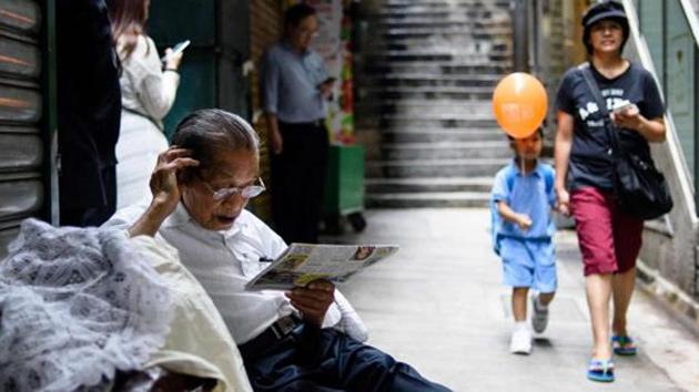 An elderly man reads a newspaper in an alleyway in Hong Kong. (AFP File Photo) An elderly man reads a newspaper in an alleyway in Hong Kong. (AFP File Photo)