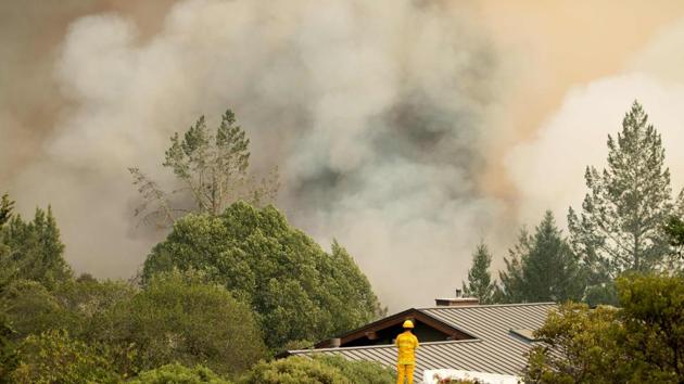 A firefighter watches smoke billow as flames approach a residential area in Sonoma in California. (AFP Photo)
