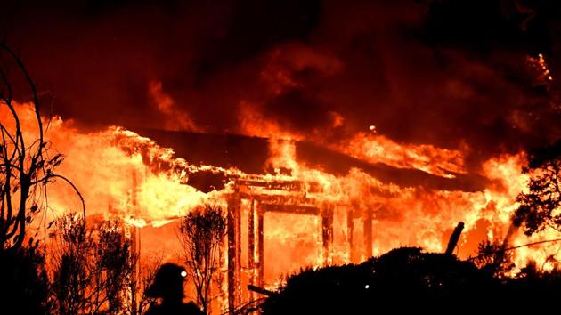 Firefighters assess the scene as a house burns in the Napa wine region of California as multiple wind-driven fires continue to ravage the area burning structures and causing widespread evacuations. (AFP Photo)