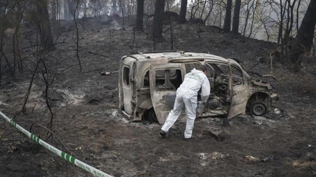 A Police scientist inspects the remains of the car where two women died after a wild fire in Pontevedra, in the northwestern Spanish region of Galicia, Spain, Monday, Oct. 16, 2017.(AP Photo)