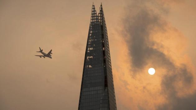 A plane flies past the Shard in central London as the sky takes on an unusual ochre yellow colour caused by Storm Ophelia picking up sand from the Sahara desert and dust from wildfires in Portugal as its winds gained force. (Dominic Lipinski / PA via AP)