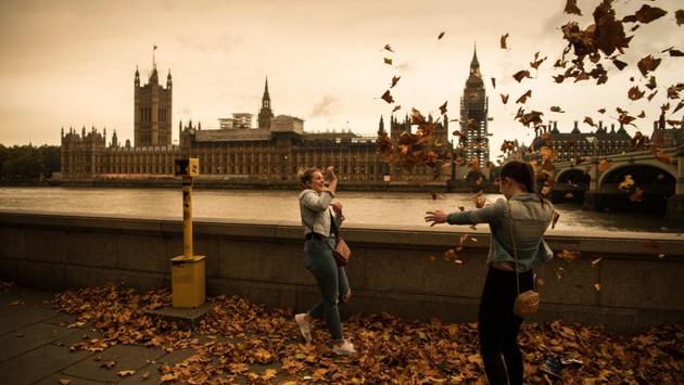 Girls throw leaves opposite the Houses of Parliament during a reddish sky caused by remnants of Ophelia on October 16, 2017 in London. This movement of air from the continent also brought in warmer temperatures, including highs of up to 22 degrees Celsius in parts of southern England, including London. (Carl Court / Getty Images)