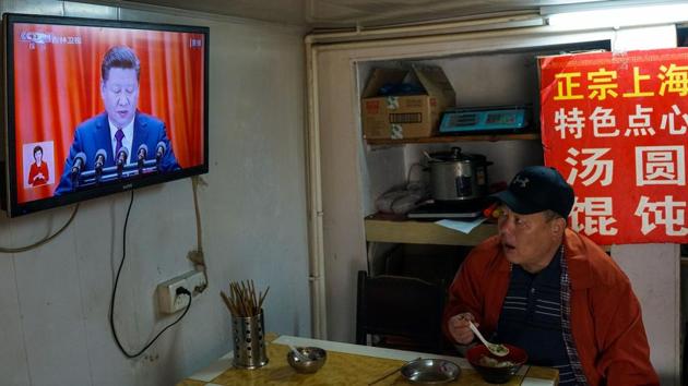 A man watches the opening speech on a television in Shanghai on October 18, 2017. Xi affirmed economic plans that call for developing state-owned companies that dominate industries including finance, energy and telecoms while also giving the market the ‘decisive role’ in allocating resources. (Chandan Khanna / AFP)