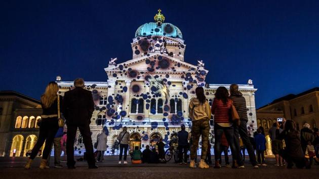 People watch as the Swiss House of Parliament is illuminated during a light show titled ‘Rendez-vous Bundesplatz’ in the Swiss capital, Bern. The show will run twice every evening until November 25, 2017. (Fabrice Coffrini / AFP)