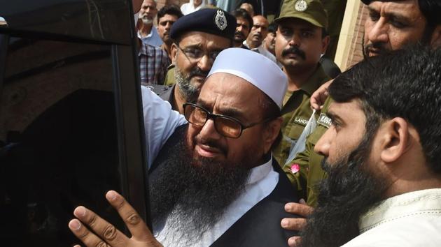 Pakistan policemen escort the head of the Jamaat-ud-Dawa, Hafiz Saeed, as he leaves the court after the expiry of his three-month detention period, in Lahore on October 17, 2017.(AFP)