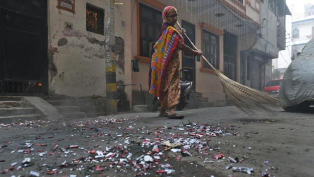 The scattered remains from bursting of firecrackers is being swept by a worker on Friday morning following Diwali. (Sushil Kumar/HT PHOTO)
