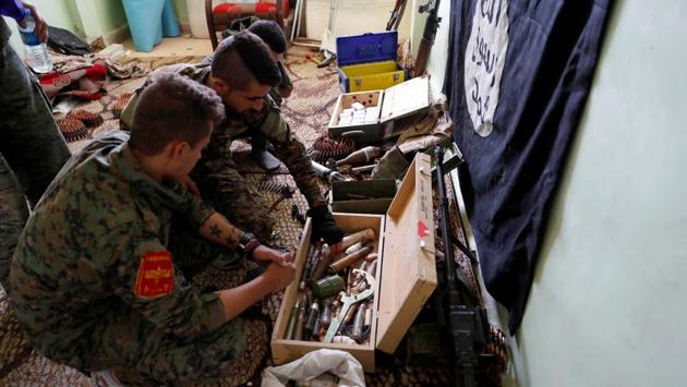 Fighters of Syrian Democratic Forces inspect weapons and munitions recovered at the former positions of the Islamic State inside a building at the frontline in Raqqa, Syria on October 7, 2017. (Erik De Castro / REUTERS)