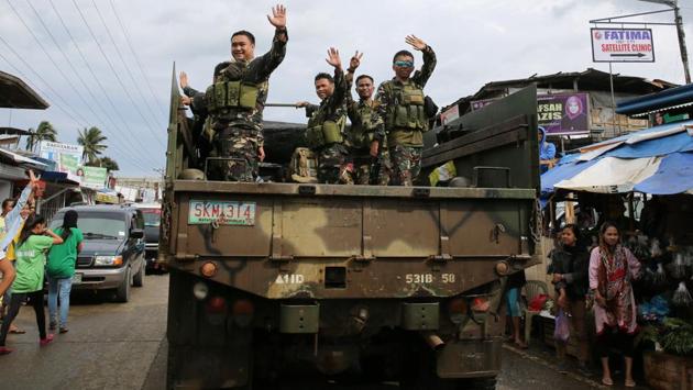 Government troops wave as they travel back from their five-month stint against pro-ISIS militant groups on October 20, 2017. Army trucks crawled through the deserted streets to take displaced people to safe areas, while echoes of gunfire and explosions could still be heard from troops engaging the remaining Maute group militants hemmed into a shrinking battle zone. (Romeo Ranoco / REUTERS)