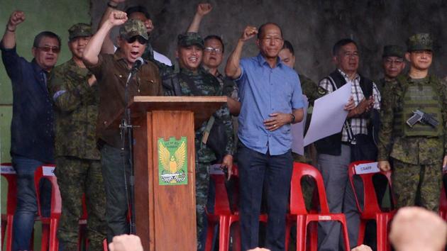 Philippine President Rodrigo Duterte (on stage in brown) raises a clenched fist declaring Marawi ‘liberated from terrorist influence’ on October 17, 2017. The military however has said the five-month battle against militants loyal to the Islamic State was not yet completely over despite cleanup efforts being initiated. (Ted Aljibe / AFP)