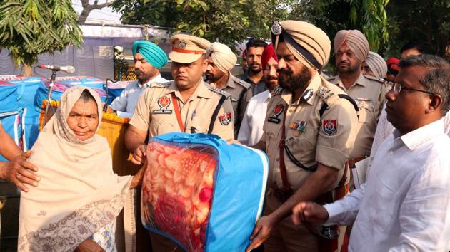 Bathinda zone IGP MS Chhina handing over a blanket to a Punjab police martyr’s family member during an event to observe Police Commemoration Day in Bathinda on Saturday. (Sanjeev Kumar/HT)