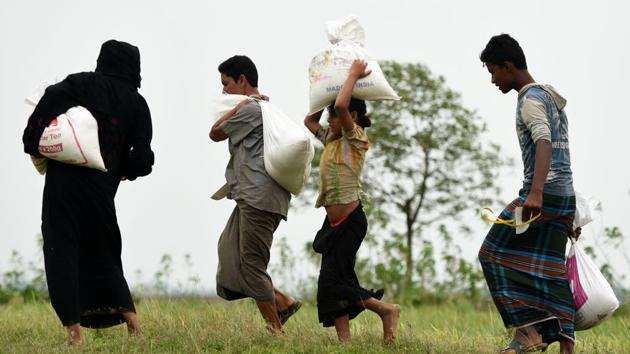 Rohingya Muslim refugees carry relief aid at Nayapara refugee camp in Teknaf on October 21, 2017. Thousands of Rohingya Muslims stranded near Bangladesh's border this week after fleeing violence in Myanmar have finally been permitted to enter refugee camps after "strict screening", officials said. (AFP) Rohingya Muslim refugees carry relief aid at Nayapara refugee camp in Teknaf on October 21, 2017. Thousands of Rohingya Muslims stranded near Bangladesh's border this week after fleeing violence in Myanmar have finally been permitted to enter refugee camps after "strict screening", officials said. (AFP)