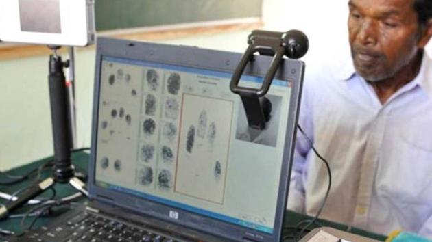 A man looks on as another puts his hand on a slap pad to record fingerprints during a data collection process of Unique Identification Authority of India. (AFP File) A man looks on as another puts his hand on a slap pad to record fingerprints during a data collection process of Unique Identification Authority of India. (AFP File)