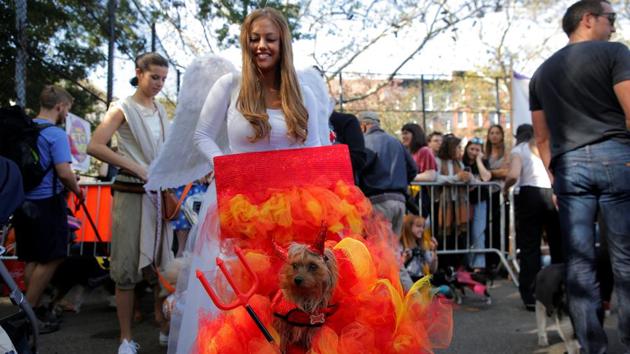 A woman dressed as an angel pushes her dog dressed like the devil in the annual Halloween dog parade at Manhattan’s Tompkins Square Park. (Lucas Jackson / REUTERS)