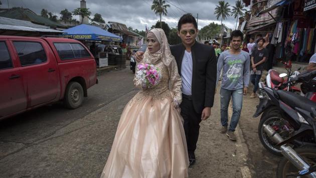 Katty Malang Mikunug (L), and Paulo Mamayo Ambor (R) walk on a street on their wedding day. President Rodrigo Duterte‘s recent visit announcing Marawi’s liberation from pro-ISIS forces has sparked hopes that hundreds of thousands of residents could soon begin returning home. (Jes Aznar / Getty Images)