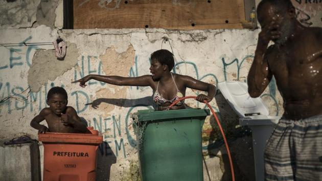 Residents bathe in large garbage cans filled with water outside their squatter building and do their best to drown out the stench from mountains of trash and rummaging pigs in the centre of the building. (Felipe Dana / AP)