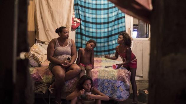 Luciana Bastos (L) watches television inside the building that used to house the IBGE. Bastos, 30, recently moved here with her husband and two daughters after they both lost their jobs and couldn’t make the rent. In July, the last month for which data is available, unemployment was close to 13%, a huge increase from 4% at the end of 2004. (Felipe Dana / AP)