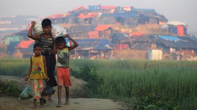 Rohingya refugee children carry supplies with Balukhali refugee camp seen on a hillock near Cox’s Bazar on October 23, 2017. More than 300,000 children are among the refugees. Mark Lowcock, U.N. humanitarian coordinator, announced that many were acutely malnourished. (Hannah McKay / REUTERS)