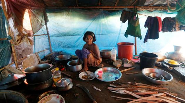 10-year-old Ruzina Akhter, whose parents died while crossing the Myanmar border, cooks food inside a shelter at a refugee camp in Palong Khali near Cox's Bazar on October 22, 2017. (Adnan Abidi / REUTERS)