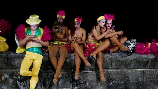 Dancers use an internet hotspot before performing at the Carnival of Havana. Given the relative expense of connecting to the internet, Cubans use it mostly to stay in touch with relatives and friends. Although prices have dropped, the $1.50 hourly tariff represents 5% of the average monthly state salary of $30. (Alexandre Meneghini / REUTERS)
