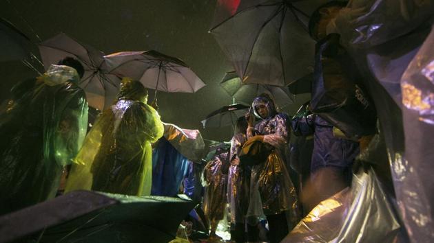 Thai people in raincoats queue up ahead of the cremation ceremony, on October 24, 2017. The exactingly planned funeral is governed by strict protocols. Men must wear a black suit, have short hair and be clean-shaven, while women must wear a black skirt below the knees and not have highlights in their hair. Even colourful mobile phone cases have been outlawed and royals must not be photographed eating or walking up or down stairs. (Wason Wanichakorn / AP)