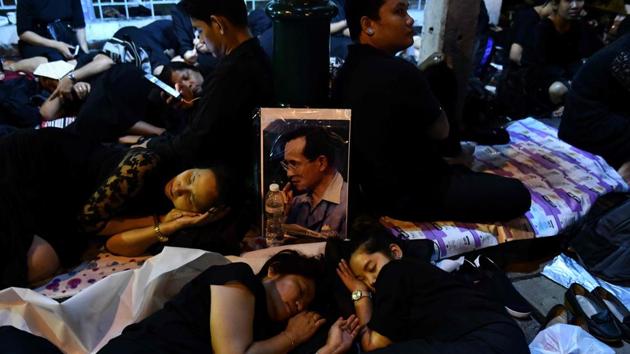 Mourners sleep in front of an image of the late Thai King Bhumibol Adulyadej waiting for his funeral procession on October 26, 2017. About 200,000 black-clad mourners thronged Bangkok’s historic quarter before dawn to witness elaborate gilded processions that will be broadcast live. (Anthony Wallace / AFP)