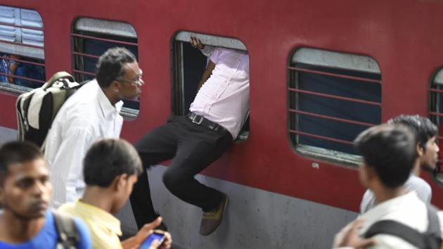 A passenger uses the emergency window to enter the Sampoorna Kranti Express which runs between Patna and New Delhi on Sunday. Massive rush was witnessed at New Delhi railway station as people leave for Bihar and UP for Chhath Puja. (Arvind Yadav/HT Photo)