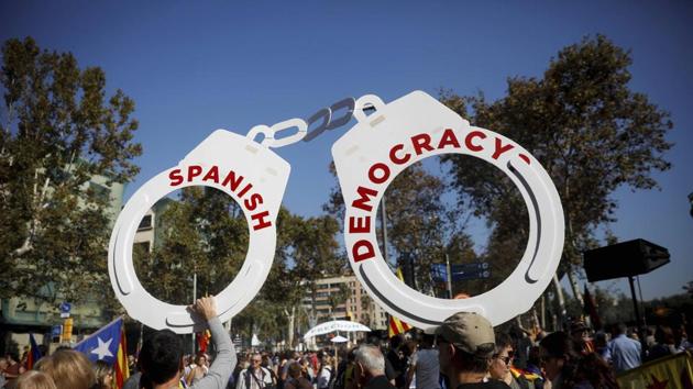 Protesters hold fake handcuffs as they take part a rally outside the Catalan parliament in Barcelona, Spain. (AP Photo)