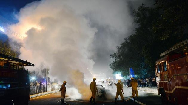 Firefighters douse a burning car outside police headquarters at ITO in New Delhi. (Ravi Choudhary / HT Photo)