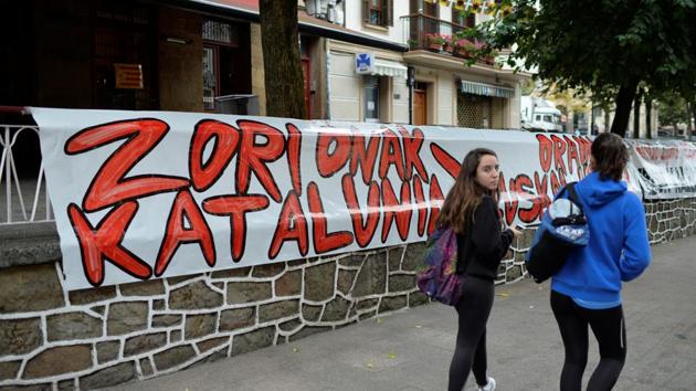 People walk past signs reading, ‘Congratulations Catalonia. Now The Basque Country’, following a unilateral declaration of independence by the Catalan parliament, in the Basque town of Guernica, Spain. (REUTERS)