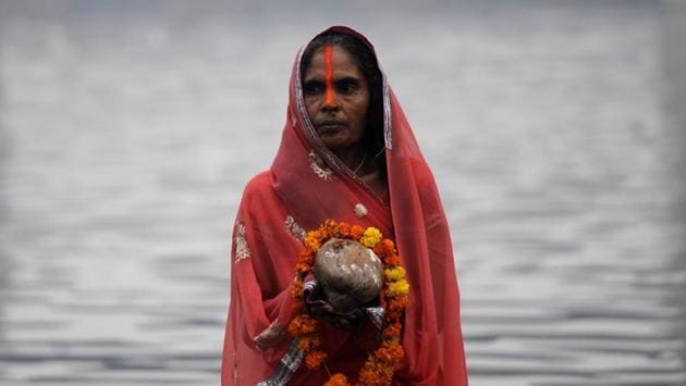 A woman offers prayers to the Sun God at sunrise on the final day of Chhath Puja at Yamuna ghat, in Noida. (Sunil Ghosh / HT Photo)
