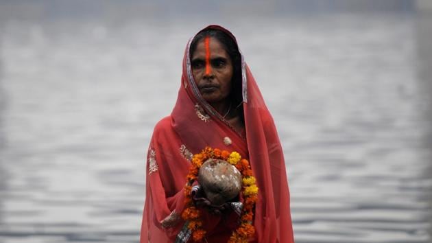 A woman offers prayers to the Sun God during sunrise on the 2nd day of Chhath festival at Yamuna ghat , in Noida. On the occasion of the final day of the puja, people converged at river banks before sunrise and offered ‘Arghya’ to the rising sun in wicker baskets. (Sunil Ghosh / HT Photo)