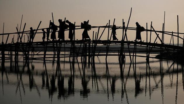Rohingya refugees cross a bamboo bridge as they arrive at a port after crossing from Myanmar in Bangladesh on October 25, 2017. (Hannah McKay / REUTERS)
