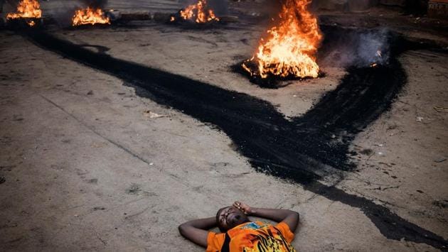 An opposition supporter lays on the street, unharmed, as he demonstrates near a burning barricade in Kibera, Nairobi, on October 25, 2017 a day before the scheduled re-election for the presidency. (Marco Longari / AFP)