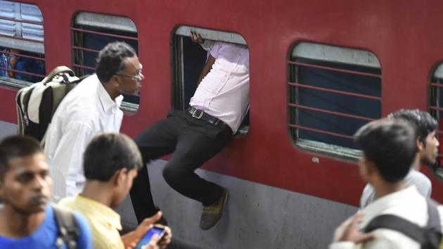 A passenger uses the emergency window to enter the Sampoorna Kranti Express, which runs between Patna and New Delhi on Sunday. Massive rush was witnessed at New Delhi railway station as people left for Bihar and UP on the occasion of Chhath Puja. (Arvind Yadav / HT Photo)
