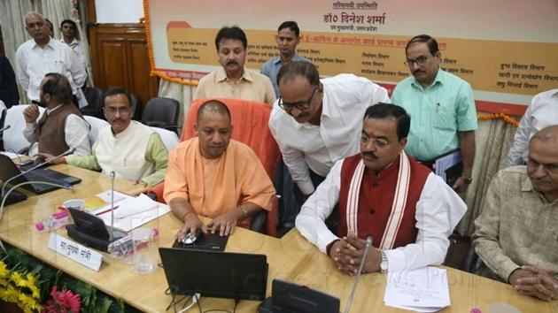 UP chief minister Yogi Adityanath transferring a file to deputy CM Dinesh Sharma to mark the beginning of paperless working.(HT)