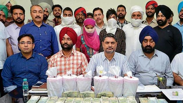 Special Task Force AIG Rashpal Singh (2nd from right) and other officials with the accused (covered faces), seized currency and 6kg heroin in Amritsar on Friday.(Sameer Sehgal/HT)