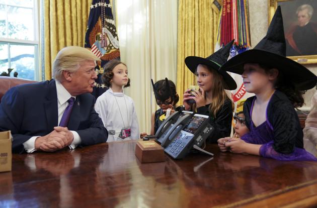 President Donald Trump talks to children dressed in Halloween costumes after handing out candy to them in the Oval Office. (AP Photo)