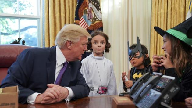 President Donald Trump talks with from left., Natalynn Parkinson, 6, Yume Inone, 6, and Phoebe Trabb, 7, who are dressed in their Halloween costumes in the Oval Office of the White House. (AP Photo)