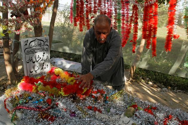 Iqbal Khan puts decorations on his son's grave in a family orchard in Swabi, Pakistan October 24, 2017. Picture taken October 24, 2017. REUTERS/Fayaz Aziz (REUTERS)