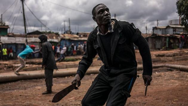 A protester brandishing a machete and a knife prepares to take cover from incoming tear gas canisters during clashes with police forces in Kibera, Nairobi, on October 26, 2017. (Marco Longari / AFP)