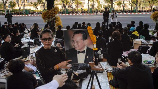 A mourner holds up an image of the late Thai king Bhumibol Adulyadej as she waits with others for his funeral procession to continue in Bangkok on October 27, 2017. (Ye Aung Thu / AFP)