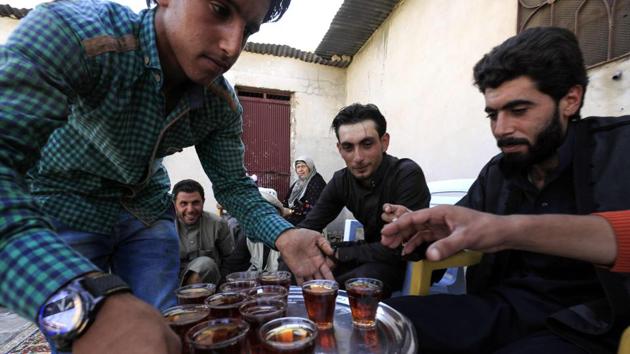 Tea was served to the groom and the guests during the wedding celebrations. Eighteen-year-old Ahmad (C) was dressed in a traditional brown robe for his wedding. (Delil souleiman / AFP) 