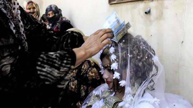 Guests showered the bride Heba (R) in cash during her wedding ceremony. ‘Before IS, there was dabke, songs and the traditional rituals of the region at our marriages, but IS banned everything, there was not a single celebration,’ a guest told AFP. (Delil souleiman / AFP) 