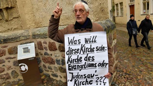 A lone protester displays a placard reading ‘What does this Church want to be: Gospel Church or ‘Jew-Pig’ Church???’ as he protests against the so-called ‘Judensau’ (Jew-Pig) sculpture in Wittenberg. (John Macdougall / AFP) 