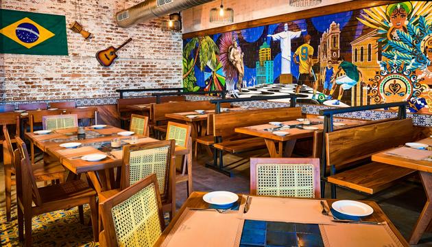 Boteco is bustling with detail — tiled tabletops, cane-backed chairs, a massive hand-painted mural (featuring football and Rio’s Christ The Redeemer statue), a guitar strung on an exposed brick wall and glimmering blue glass windows. Boteco is bustling with detail — tiled tabletops, cane-backed chairs, a massive hand-painted mural (featuring football and Rio’s Christ The Redeemer statue), a guitar strung on an exposed brick wall and glimmering blue glass windows.