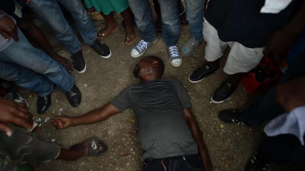 A man in a trance is seen collapsed in the National Cemetery, on November 02, 2017 in Port-au-Prince, Haiti. Baron Samdi is considered the master of death in the voodoo pantheon and is often prayed to for protection by those nearing death. (Hector Retamal / AFP) A man in a trance is seen collapsed in the National Cemetery, on November 02, 2017 in Port-au-Prince, Haiti. Baron Samdi is considered the master of death in the voodoo pantheon and is often prayed to for protection by those nearing death. (Hector Retamal / AFP)