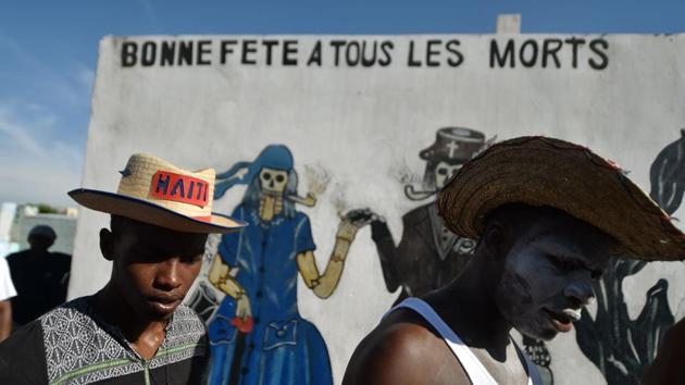 Voodoo devotees in costume take part in Fete Gede celebrations in the National Cemetery, in Port-au-Prince. A mural in the background features voodoo spirits and reads ‘Happy Birthday to all the dead’. (Hector Retamal / AFP) Voodoo devotees in costume take part in Fete Gede celebrations in the National Cemetery, in Port-au-Prince. A mural in the background features voodoo spirits and reads ‘Happy Birthday to all the dead’. (Hector Retamal / AFP)