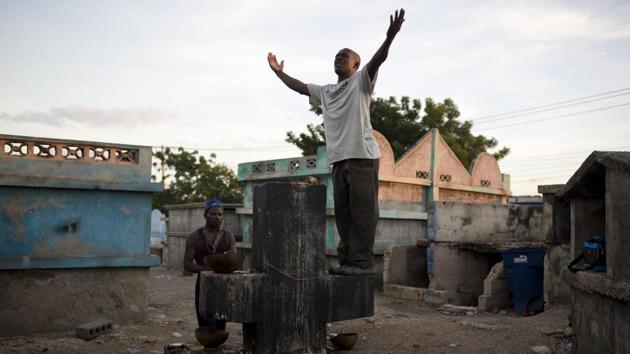 A man invokes a Gede spirit, while standing on a tomb to Baron Samdi at the Cite Soleil cemetery, in Port-au-Prince. Baron Samdi is believed to greet the recently deceased by digging up their graves and ushering their spirits into the underworld. (Dieu Nalio Chery / AP) A man invokes a Gede spirit, while standing on a tomb to Baron Samdi at the Cite Soleil cemetery, in Port-au-Prince. Baron Samdi is believed to greet the recently deceased by digging up their graves and ushering their spirits into the underworld. (Dieu Nalio Chery / AP)