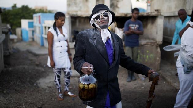 A man dressed in a black coat and glasses, holding a bottle of rum and a cigarette similar to Baron Samdi takes part in Haiti’s annual Fete Gede at the National Cemetery in Port-au-Prince. Revellers streamed into cemeteries across the country in a two-day celebration to honour Baron Samdi, the guardian of the dead, ruler of graveyards and the leader of Haitian Voodoo’s Gede spirits. (Dieu Nalio Chery / AP) A man dressed in a black coat and glasses, holding a bottle of rum and a cigarette similar to Baron Samdi takes part in Haiti’s annual Fete Gede at the National Cemetery in Port-au-Prince. Revellers streamed into cemeteries across the country in a two-day celebration to honour Baron Samdi, the guardian of the dead, ruler of graveyards and the leader of Haitian Voodoo’s Gede spirits. (Dieu Nalio Chery / AP)